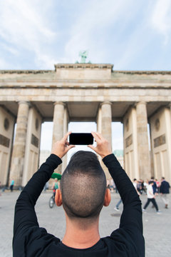 young man taking a picture of the Brandenburg Gate