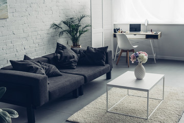 interior of modern living room with couch and workplace with laptop