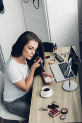 young transgender man doing makeup at workplace at home
