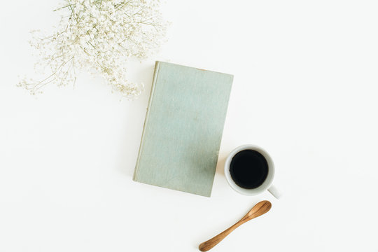 Female desk with coffee, book, flowers on white background. Flat lay, top view.