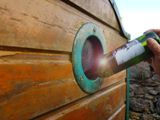 The hand throws an empty bottle in a container for broken glass.