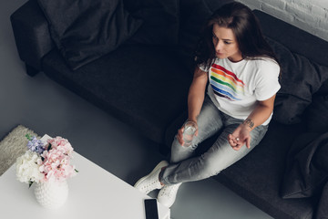 high angle view of young transgender man with pill and glass of water sitting on couch