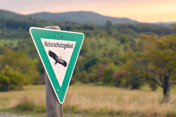 Schild Naturschutzgebiet vor einer Landschaft im Grünen