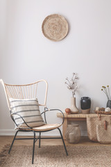 Wicker chair with striped pillow on it next to wooden table full of accessories such as vase,...