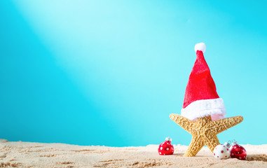Starfish with santa hat with Christmas ornaments on a beach sand - Powered by Adobe