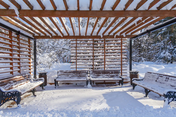 Benches under a wooden arbour in the winter forest