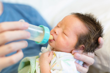 Newborn baby boy drinking from a bottle