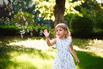 Happy baby girl standing in grass with dandelions