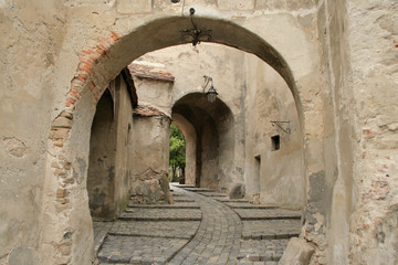 Naklejka premium Old buildings in Sighisoara, Romania. Details of Romanian architecture, walls and gates. Classic stone street.