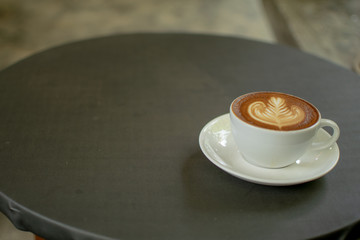 A white cup of coffee is placed on a gray table.