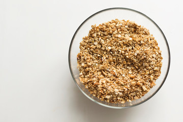 Granola in the glass plate on the white table, top view