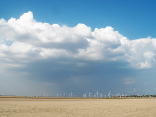 Landscape with windmills on the background of the sky and the field. Wind turbines farm. sandy beach. wind power. ecology