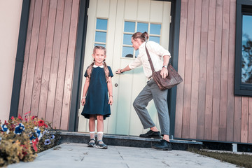 Daughter to school. Caring handsome young father leaving home with his daughter while taking her to the school