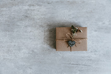 Handmade christmas gift or present box wrapped in kraft paper on wooden background. Top view, flat lay, copy space. Greeting card
