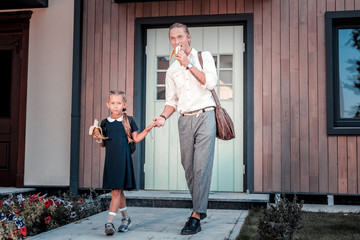Eating bananas. Busy young father and his cute daughter eating bananas leaving home in the morning