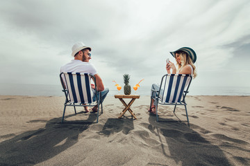 Couple on a deck chair relaxing on the beach. Happy couple enjoy on the beach during summer vacations