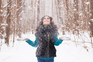 Fototapeta na wymiar Happy young woman plays with a snow at snowy forest outdoor