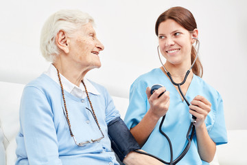 Pflegekraft macht Blutdruckmessung bei Seniorin