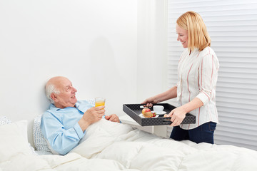Kranker Senior beim frühstücken im Bett