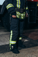 partial view of firefighter in protective fireproof uniform standing at fire department