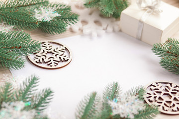 Fototapeta na wymiar Christmas composition. Christmas gift, wooden snowflakes and figurines, pine cones, fir branches on wooden white ba