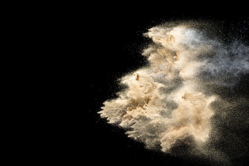 Dry river sand explosion. Golden colored sand splash against  black background.