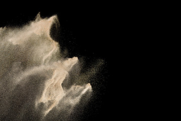 Dry river sand explosion. Golden colored sand splash against  black background.