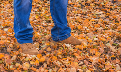 men's feet in the woods on the leaves of autumn. walk through the autumn forest.