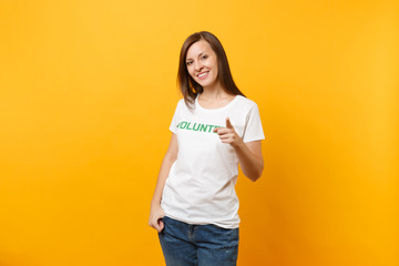 Portrait of happy smiling satisfied woman in white t-shirt with written inscription green title volunteer isolated on yellow background. Voluntary free assistance help, charity grace work concept.