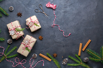 Packing Christmas gifts. Christmas gift boxes and decorations, pine branches on dark  table. Present decorated with natural parts Top view with copy space