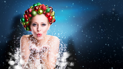 Weihnachtlich geschmückte Frau pustet Schnee 