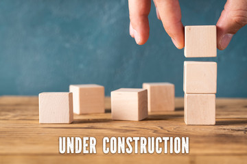 hand is stacking blank cubes and the message "under construction"