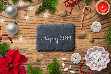 piece of slate with message "Happy 2019" and christmas decoration on wooden background