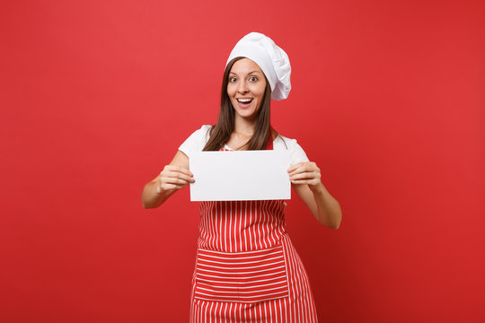 Housewife female chef cook or baker in striped apron white t-shirt toque chefs hat isolated on red wall background. Woman hold blank sign board, place for promotional text. Mock up copy space concept.