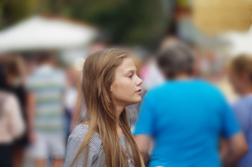 Portrait of a teenage girl on a background of people in a big city.  loneliness among people