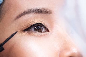 A woman is using eyeliner.