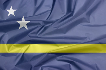 Fabric flag of Curacao. Crease of Curacao flag background, blue field with a horizontal yellow stripe slightly below the midline and two white stars.