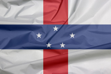 Fabric flag of Netherlands Antilles. Crease of Netherlands Antilles flag background, white with vertical red and horizontal blue and five white stars.