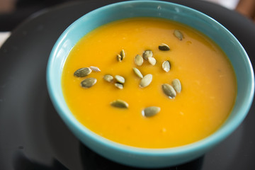 Blue bowl with pumpkin soup seasoned with seeds