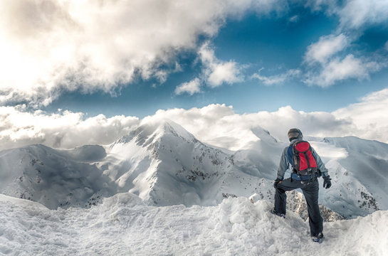 skier stay with skis on big rock on mountains backdrop. Bansko, Bulgaria