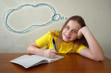 Happy girl writing in notebook placed on wooden desktop and dreaming with thought bubble on...