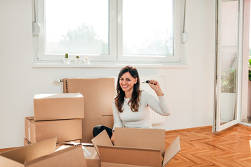 Smiling brunette at new home. Looking at camera and holding a key.