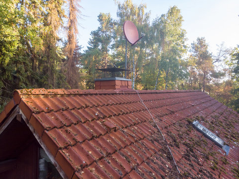 Inspection of the red tiled roof of a single-family house, inspection of the condition of the tiles on one roof side.
