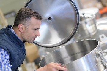 worker looking inside metal vat