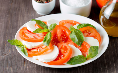 Close-up photo of caprese salad with ripe tomatoes, basil, buffalo mozzarella cheese. Italian and Mediterranean food concept. Fresh and healthy organic meal. Starter and antipasti. 