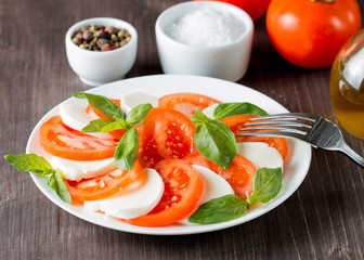 Close-up photo of caprese salad with ripe tomatoes, basil, buffalo mozzarella cheese. Italian and Mediterranean food concept. Fresh and healthy organic meal. Starter and antipasti. 