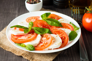 Close-up photo of caprese salad with ripe tomatoes, basil, buffalo mozzarella cheese. Italian and Mediterranean food concept. Fresh and healthy organic meal. Starter and antipasti. 
