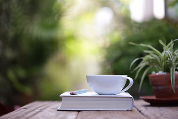 White cup with plant and notebooks