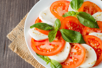 Close-up photo of caprese salad with ripe tomatoes, basil, buffalo mozzarella cheese. Italian and Mediterranean food concept. Fresh and healthy organic meal. Starter and antipasti. 