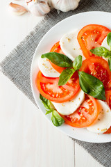 Close-up photo of caprese salad with ripe tomatoes, basil, buffalo mozzarella cheese. Italian and Mediterranean food concept. Fresh and healthy organic meal. Starter and antipasti. 
